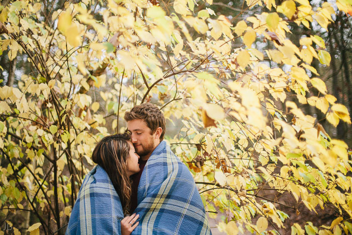 engagement session in the woods, surrounding a fire with smores and flannel in autumn
