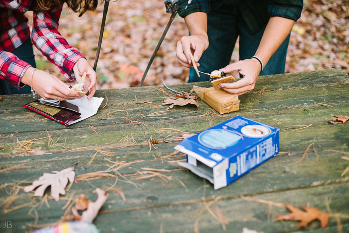 engagement session in the woods, surrounding a fire with smores and flannel in autumn
