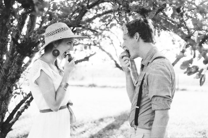 dreamy vintage engagement in an orchard kiss behind vintage straw hat camera color film fuji400h medium format vibrant