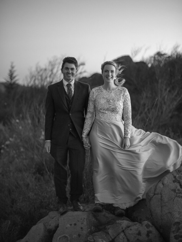 black and white photograph of wind blowing brides dress at sunrise