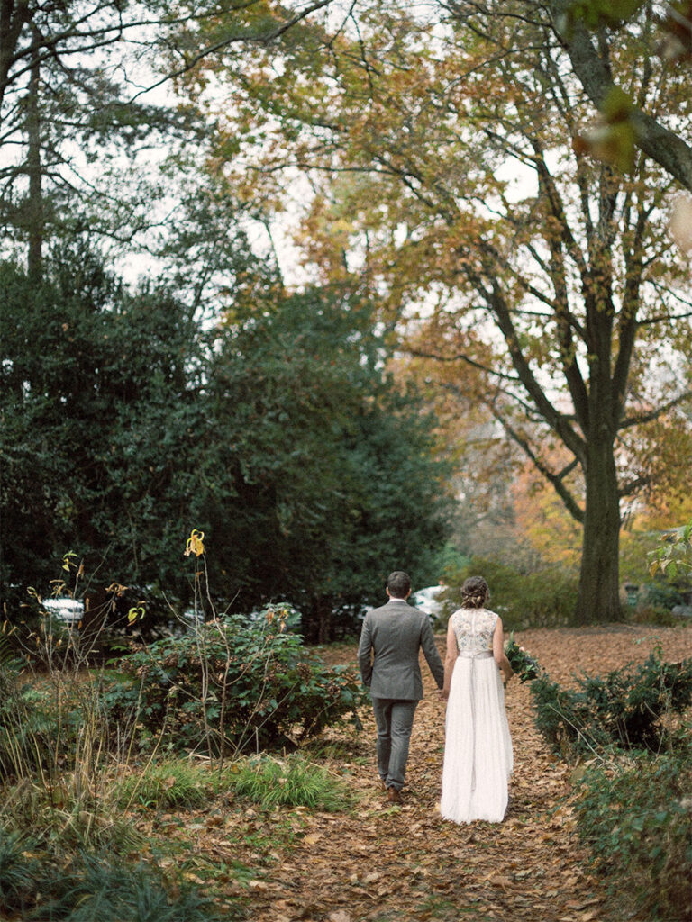 bride and groom walking at Awbury Arboretum on rainy November day