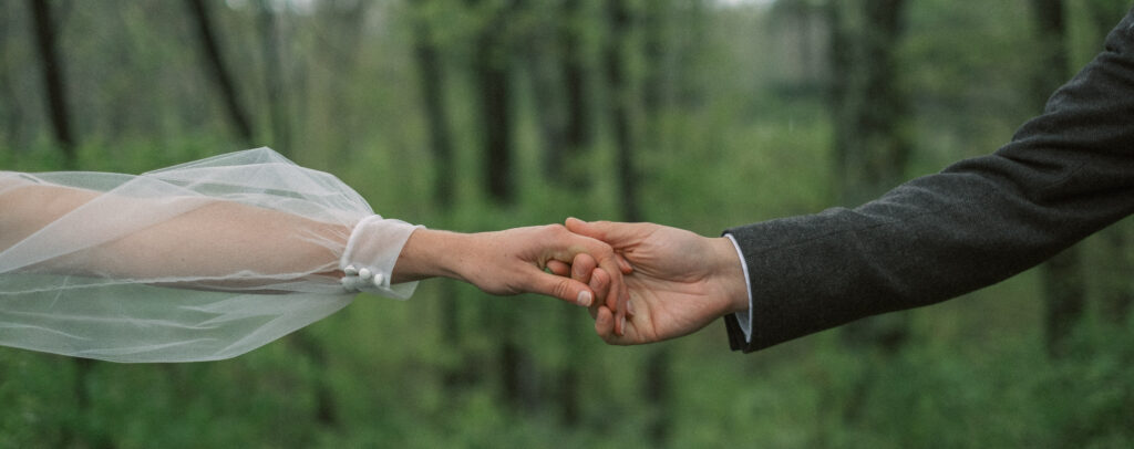 closeup of bride and groom holding hands on overcast day - natural edit - panorama