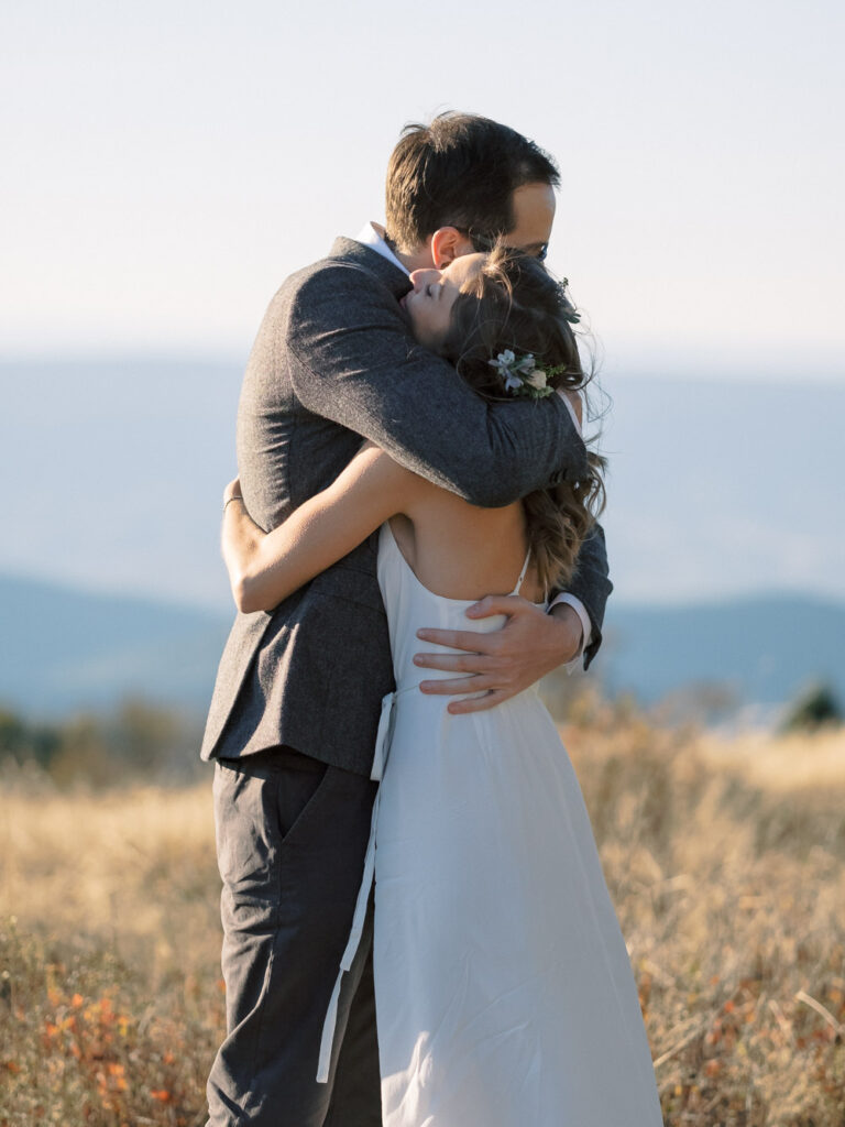 Bride and groom hugging portrait with mountain backdrop in Shenandoah National Park - natural edit