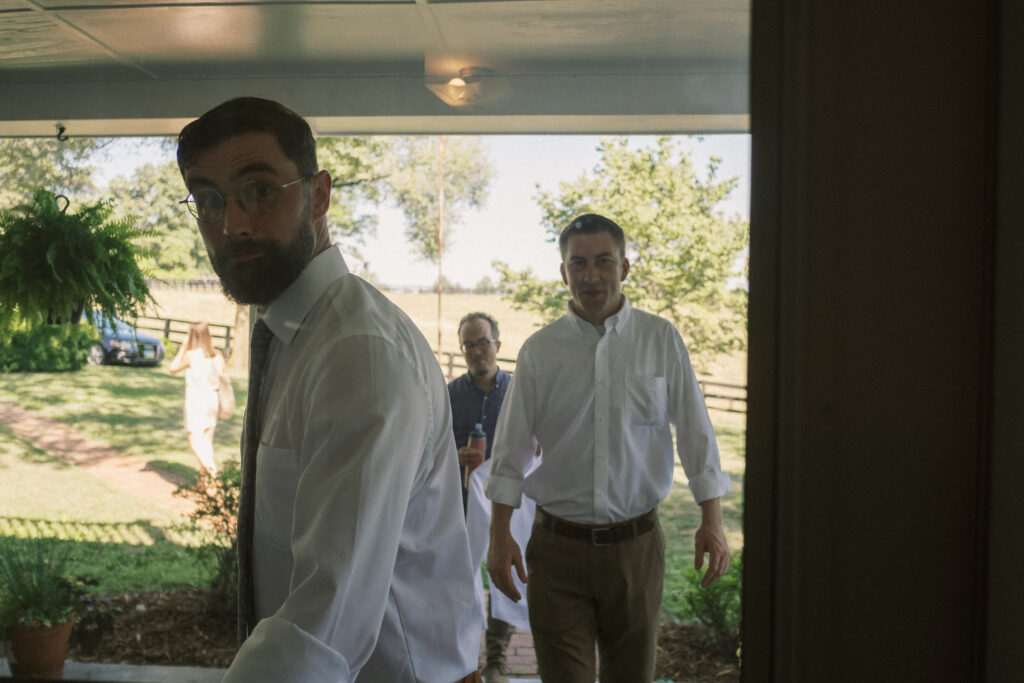 photojournalistic style wedding photography groomsmen entering farmhouse to get ready - film look 160C Virginia documentary wedding photographer