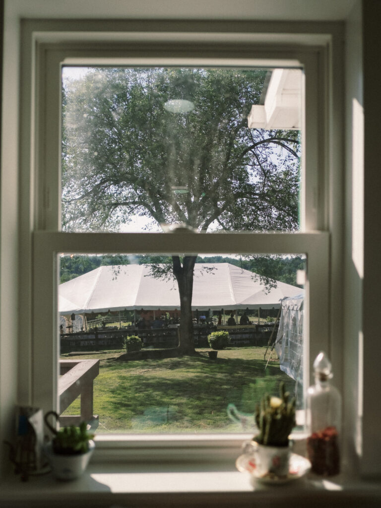 looking out of farmhouse kitchen window at Wedding tent - film look 160C Virginia documentary wedding photographer