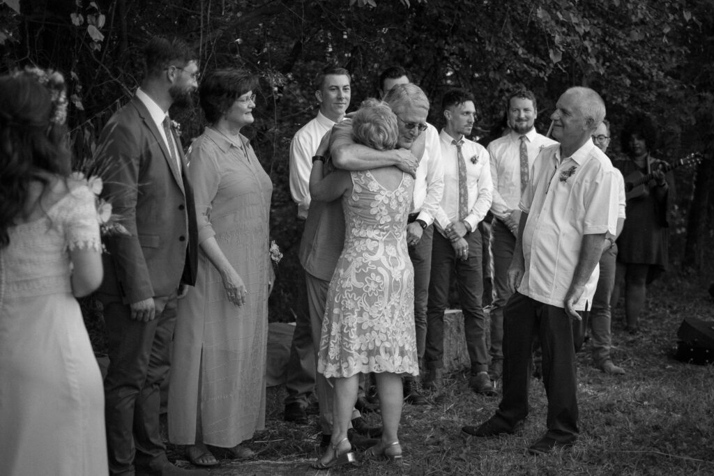 mother of bride hugging father at outdoor wedding ceremony - Ilford HP5+ black and white film look photographer
