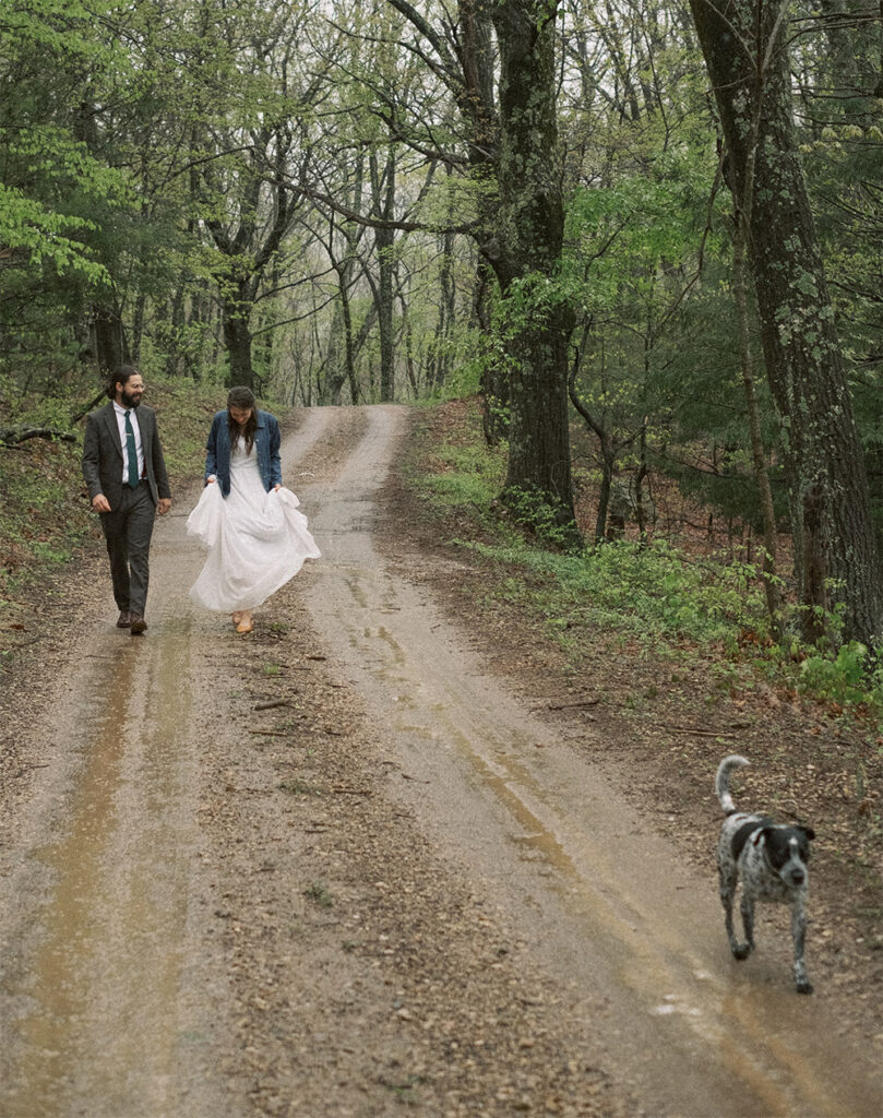 bride and groom walking dog on road to Haines chapel on rainy day wedding - natural edit