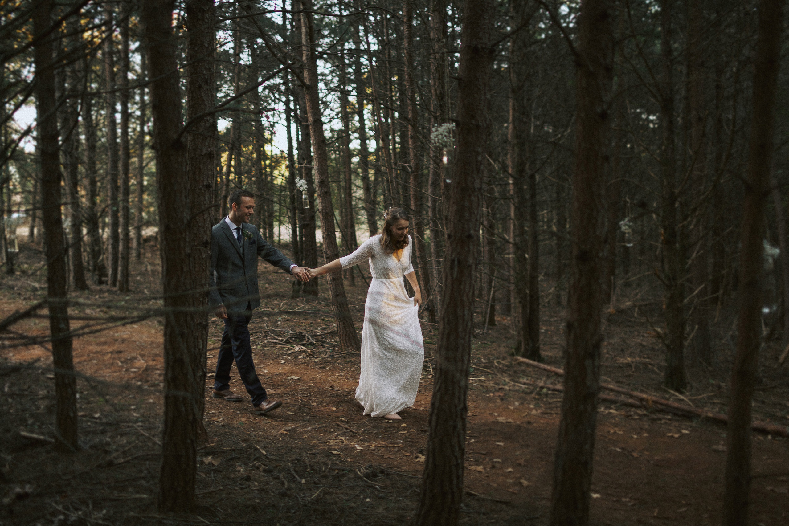 wedding couple walking through Virginia woodland forest at dusk - captured by Virginia documentary wedding photographer - fujifilm classic wedding photo