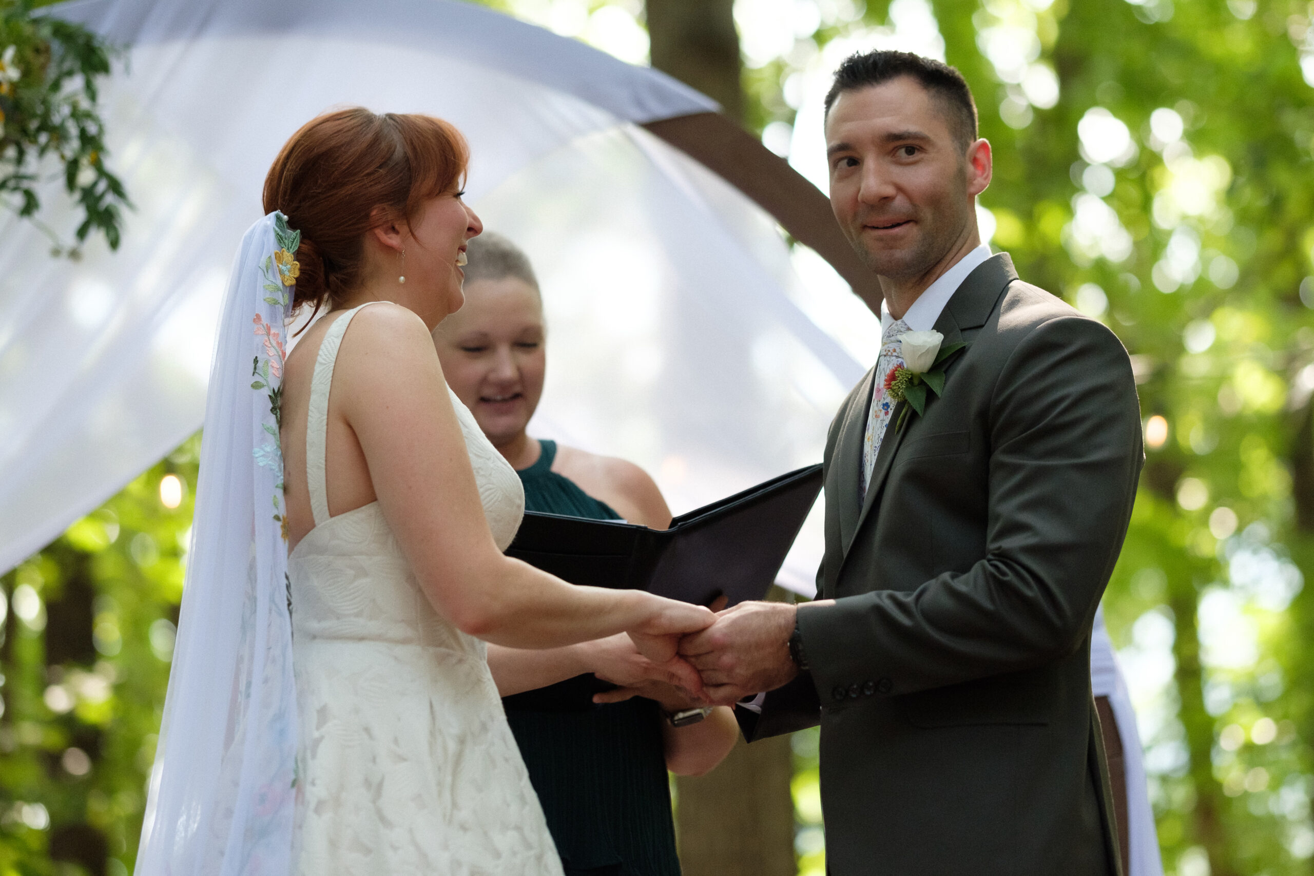 candid moment during wedding ceremony in the woods at the indigo house - groom smirking looking into the audience - natural wedding day photography - unstaged virginia wedding photography with true to life colors